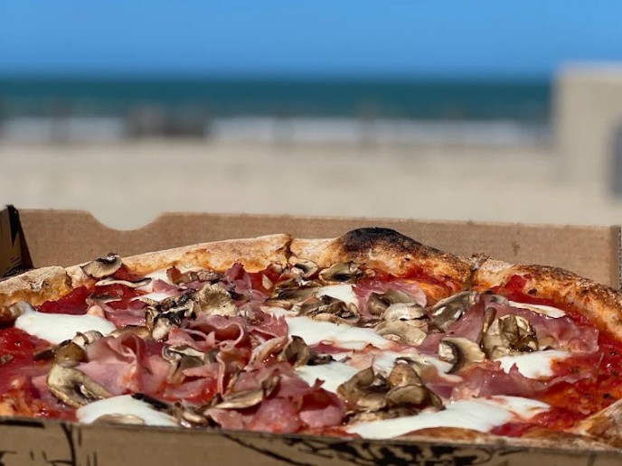 Une pizza Regina dans son carton, face à la plage de Soulac